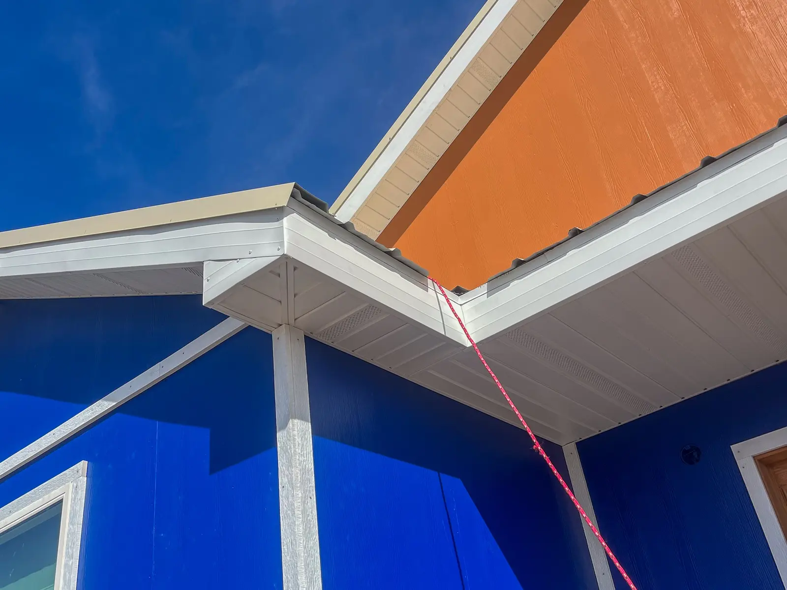 White soffit and fascia below an orange gable against a blue sky