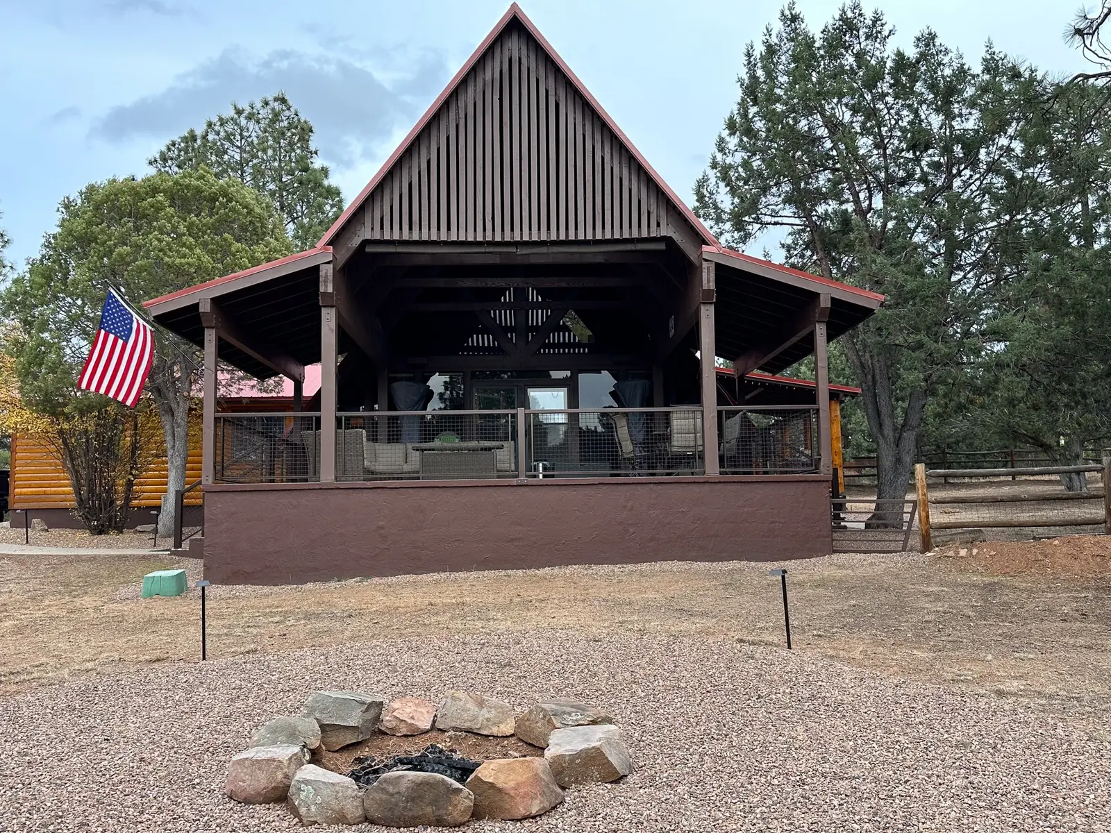 Roofed timber outdoor structure with screened sides and a surrounding yard