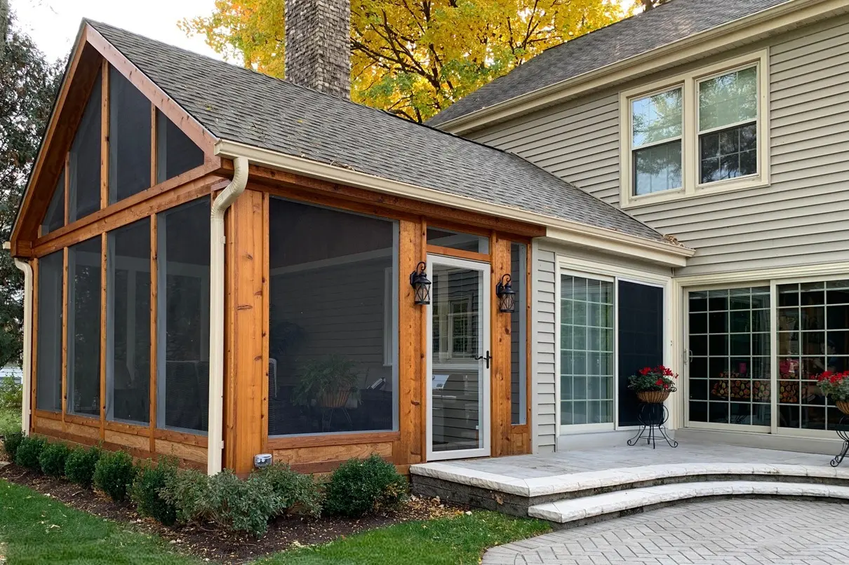 Screened porch with a timber frame beside a house